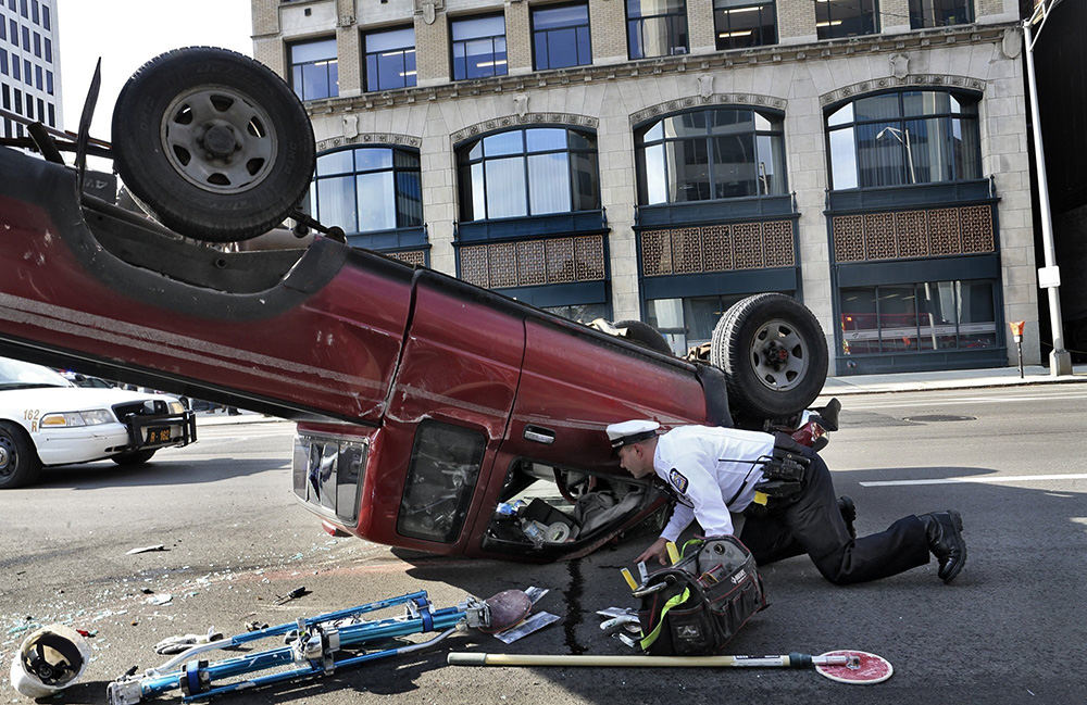 Spot News - 1st place   - Columbus police officer Ace Trask inspects an over-turned pickup truck on N. 4th St. Two vehicles were involved in the wreck.  (Eric Albrecht / The Columbus Dispatch)